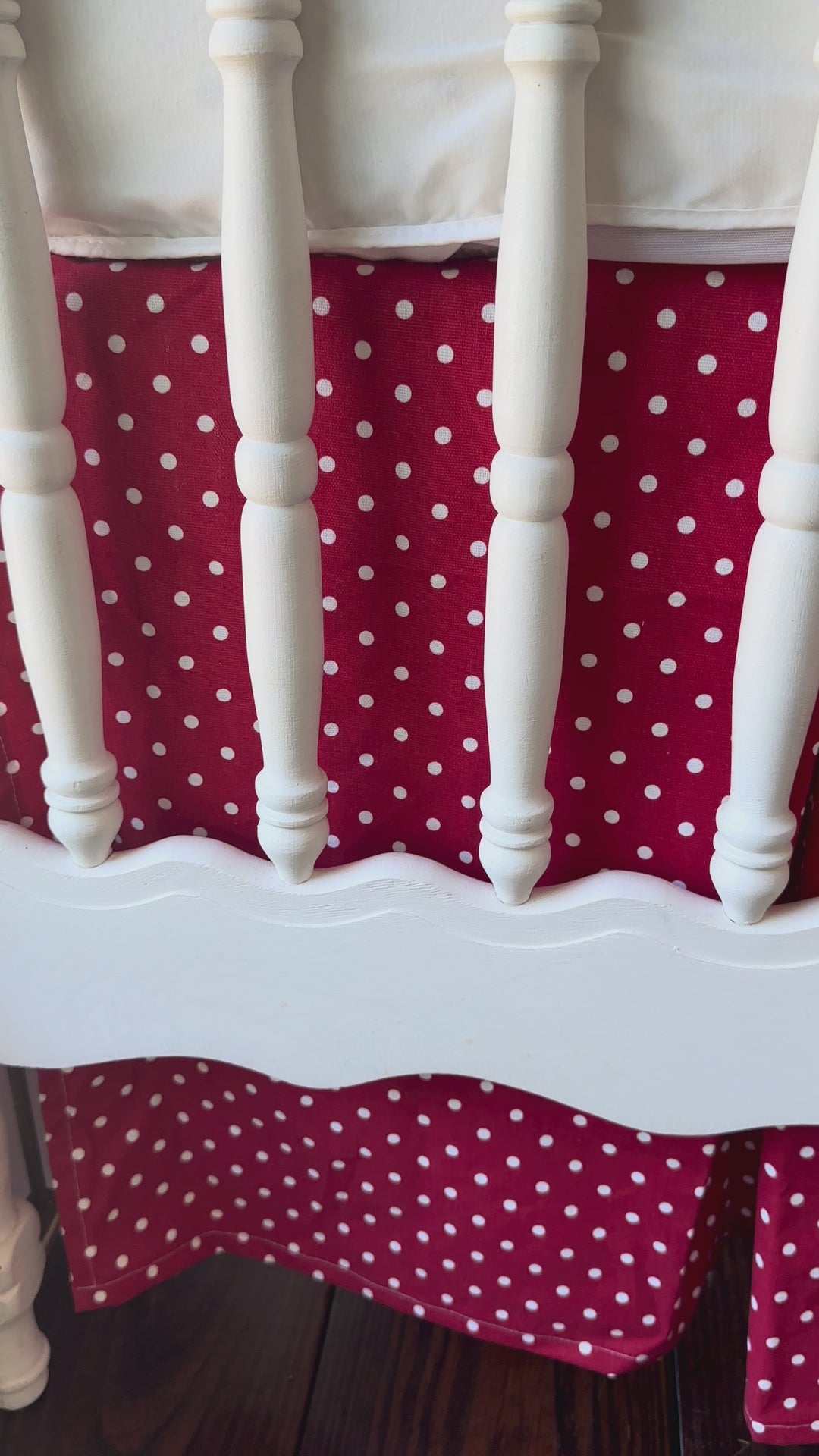 Walking video of the cherry red and white polka dot tailored crib skirt on a white spindle crib