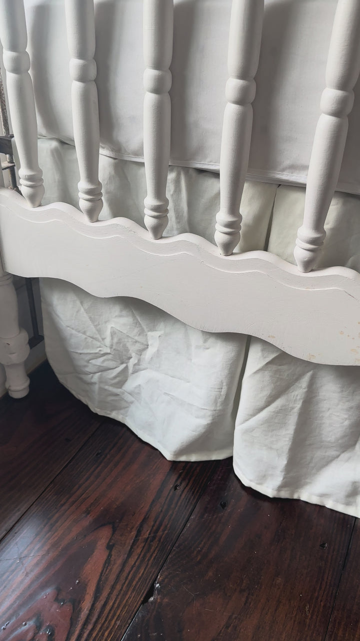 Video showing a neutral tailored crib skirt on a white crib by High Cotton Textile