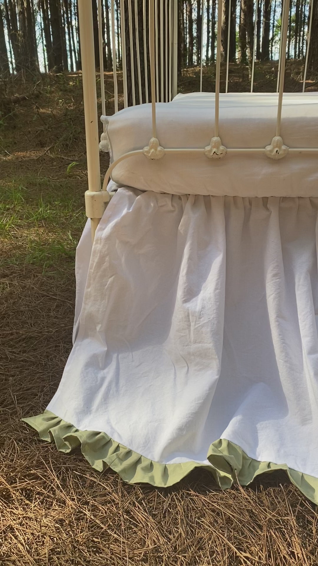 Video Overhead close-up of white gathered crib skirt with sage green ruffle trim on iron crib, two-tone heirloom nursery bedding