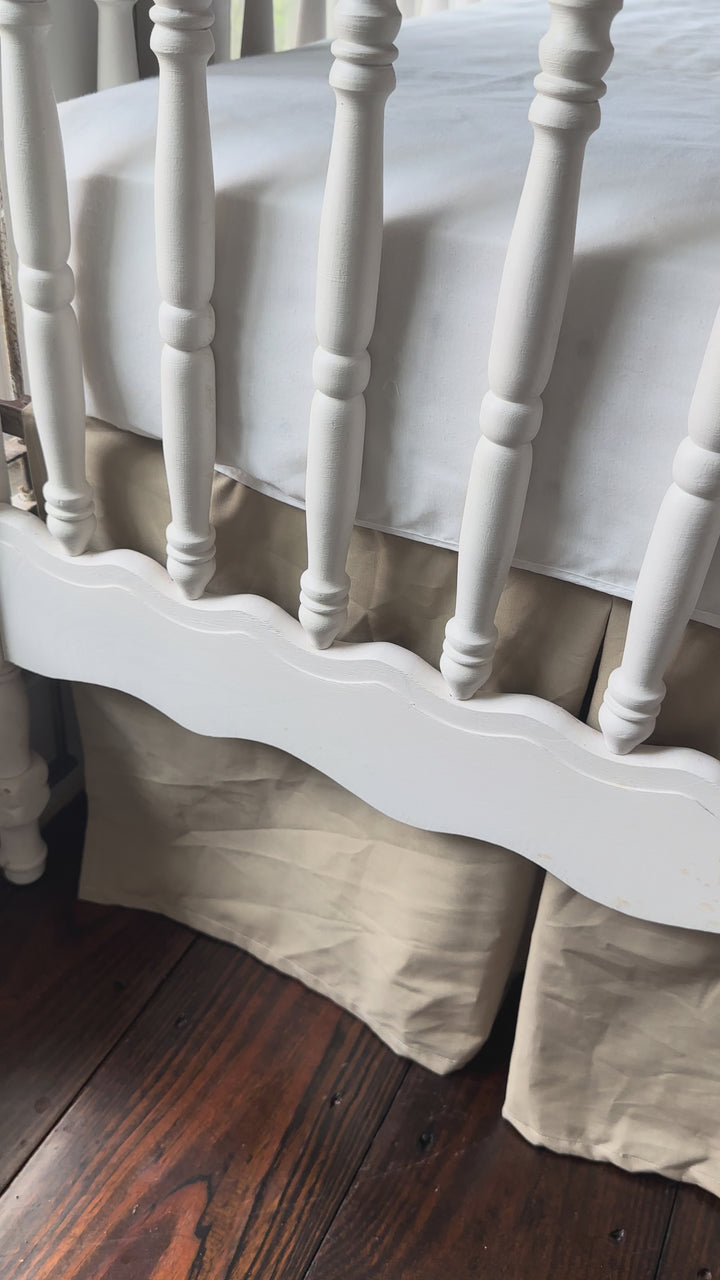 Video of oatmeal tailored cotton crib skirt on a white spindle crib in a farmhouse nursery - High Cotton Textile