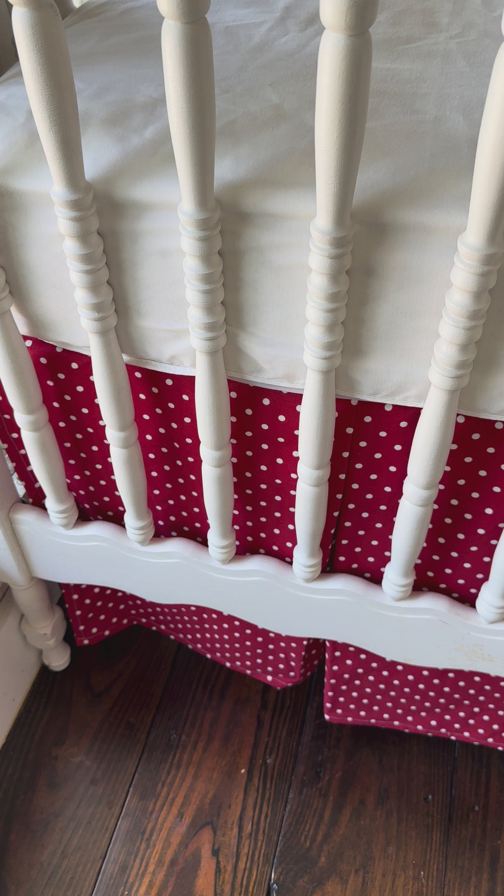 Walking video of the red and white polka dot tailored crib skirt with two white sashes tied at the posts