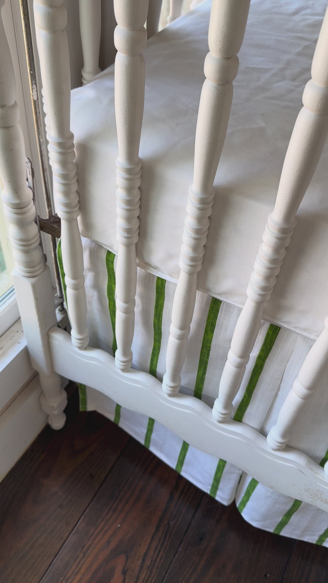 Walking video of the cypress green and white striped tailored crib skirt with two solid green sashes at the posts