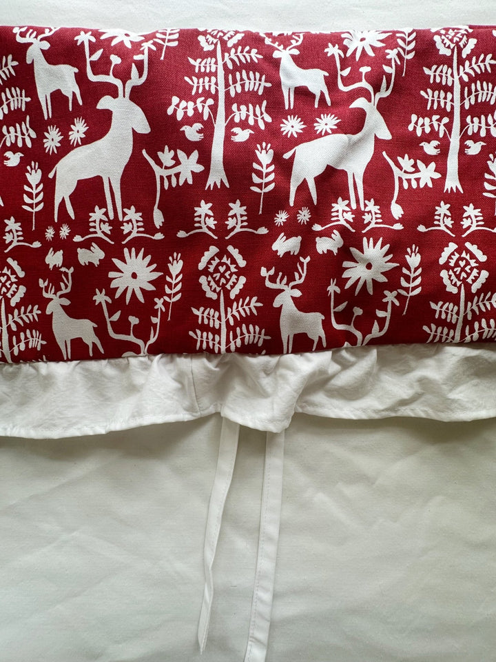 Close view of the cranberry deer print, the gathered white ruffle and one tiny white tie