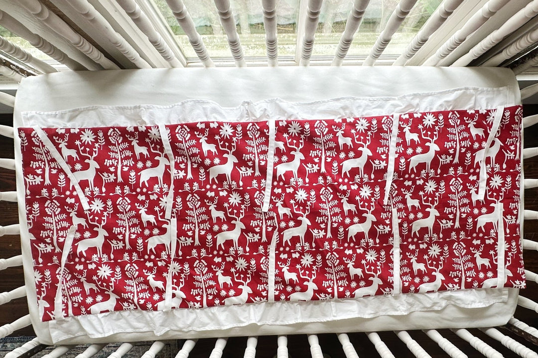 The folk deer rail cover laid flat across a white crib sheet, white ties spread out