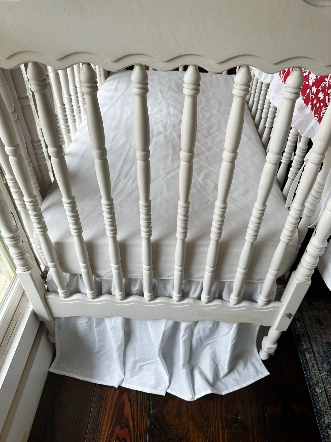 Detail of the soft gathers along the white farmhouse crib skirt beneath the mattress