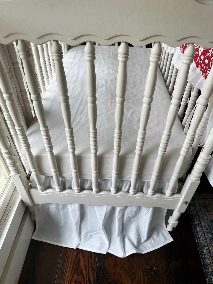 Detail of the soft gathers along the white farmhouse crib skirt beneath the mattress