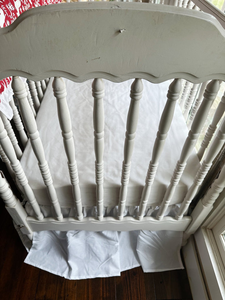 Foot of the crib showing the white farmhouse skirt gathered evenly to the floor