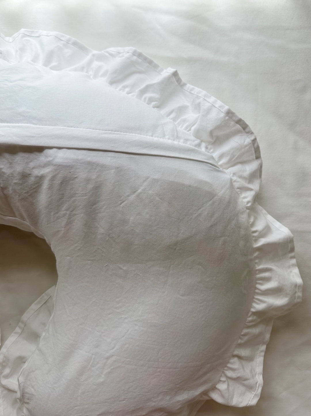 Side view of white ruffled Boppy nursing pillow cover showing the seam