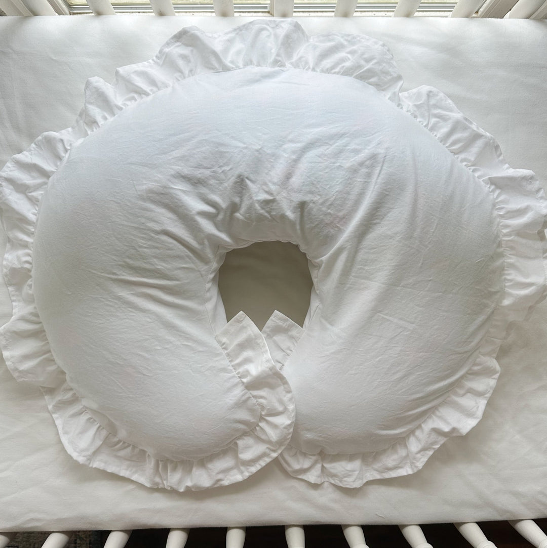 Overhead view of white ruffled Boppy pillow cover on a crib mattress