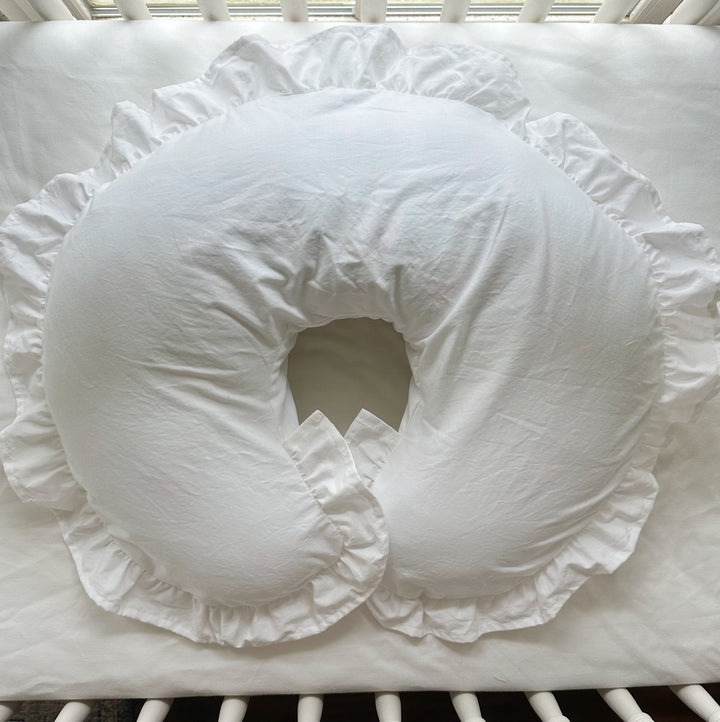 Overhead view of white ruffled Boppy pillow cover on a crib mattress