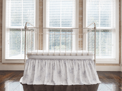 Lavender Shabby Chic Floral farmhouse crib skirt with gathered 20-inch drop, shown on an iron crib