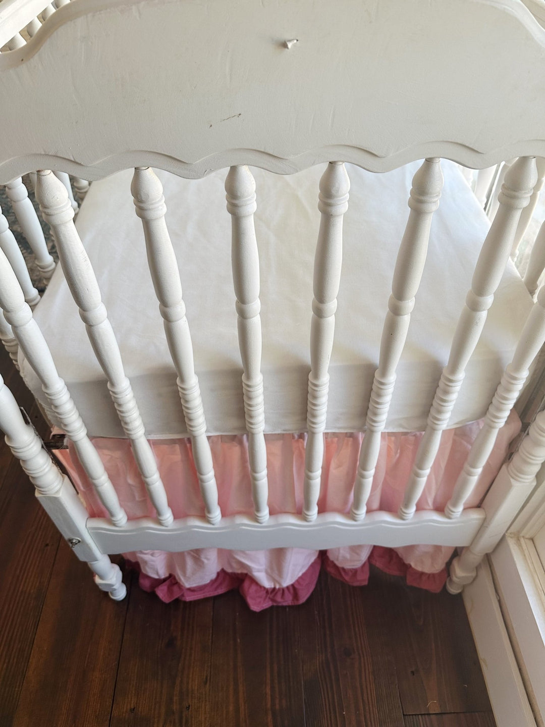 Looking down over the scalloped footboard at the white mattress, with the Sisters Pink skirt and blush ruffle beneath