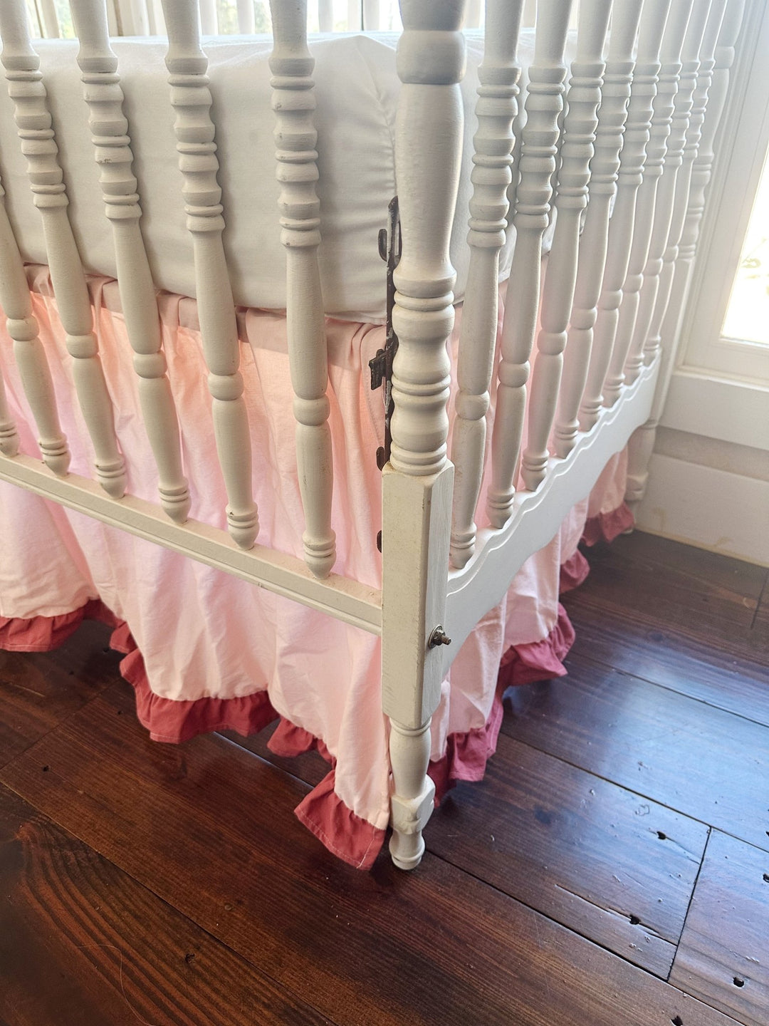Low view of the crib corner, Sisters Pink skirt gathered evenly around the post with blush ruffle at the hem