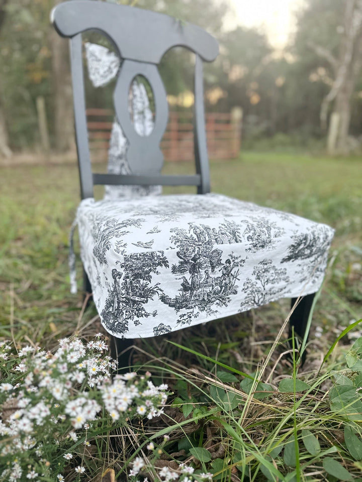 Tailored toile chair seat slipcover with a straight fitted skirt on a black wood chair at sunset