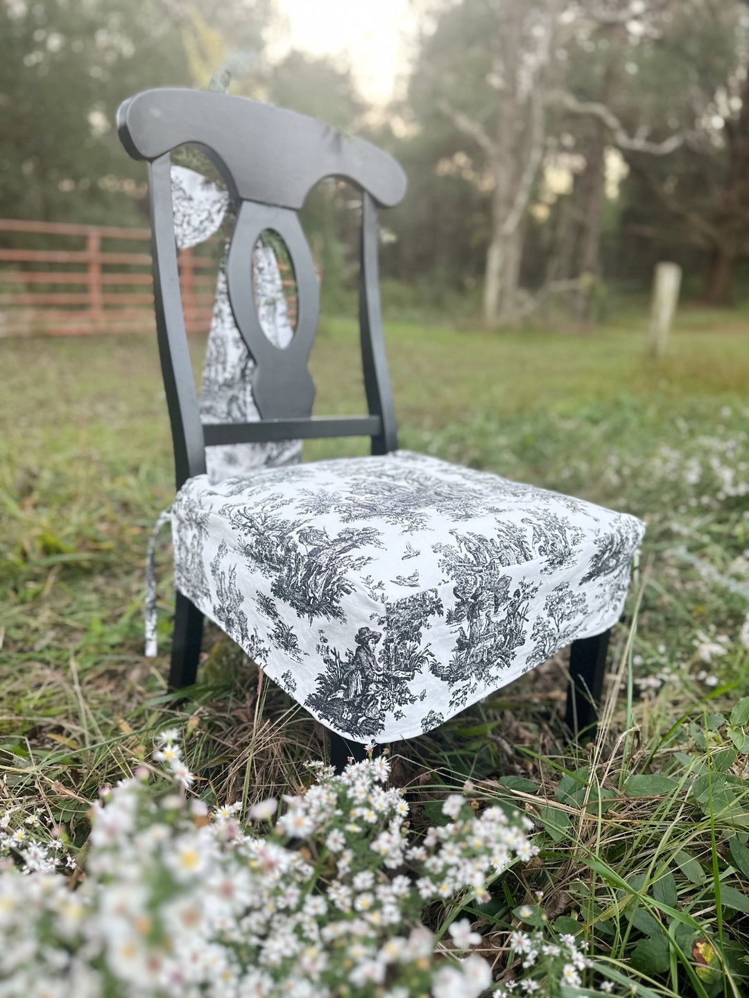 Black and white toile seat cover on a Napoleon style dining chair outdoors