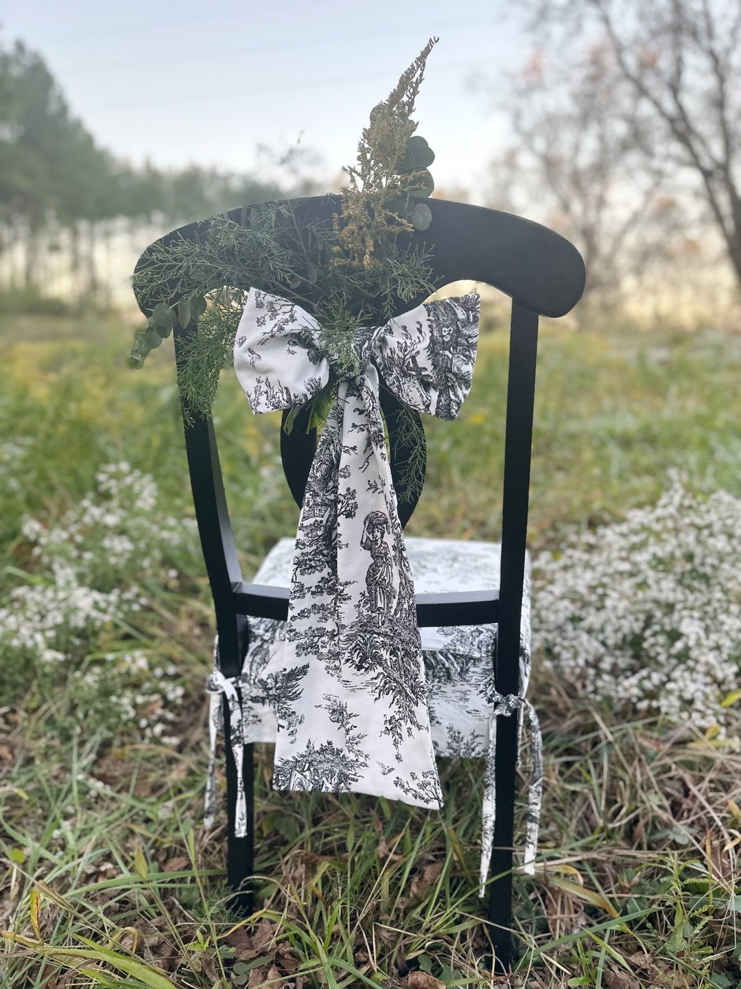 Dining chair dressed in toile with a sprig of goldenrod tucked into the bow