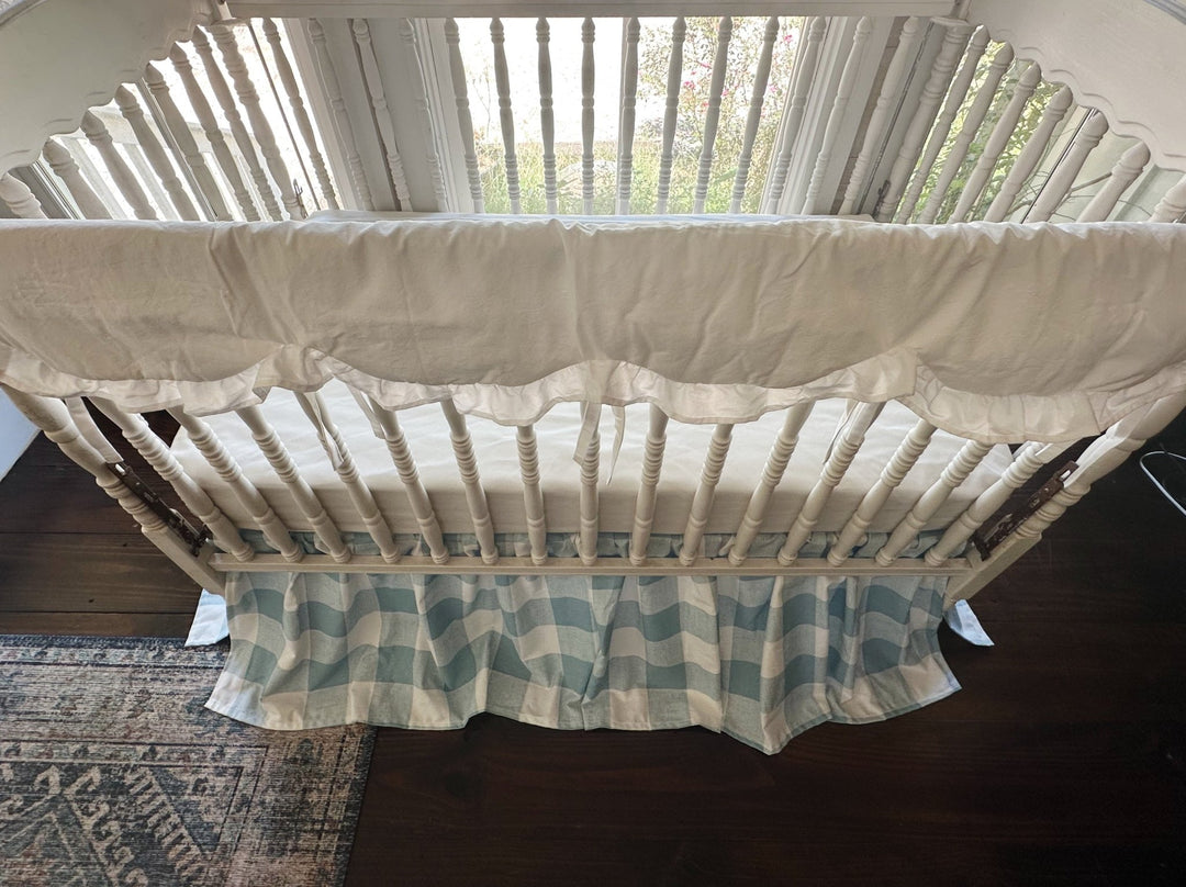 Overhead view of the white ruffled crib rail cover draped over the long rail of a Jenny Lind style crib