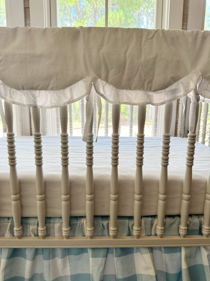 Close-up of the white scalloped edge, ruffle trim and cotton ties on the handmade crib rail cover