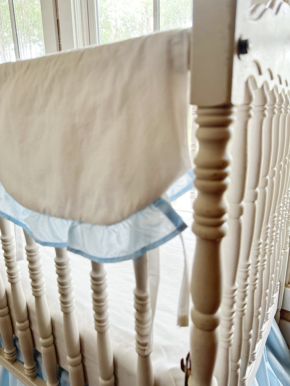 The rail cover folding over the top rail beside the crib's turned corner post