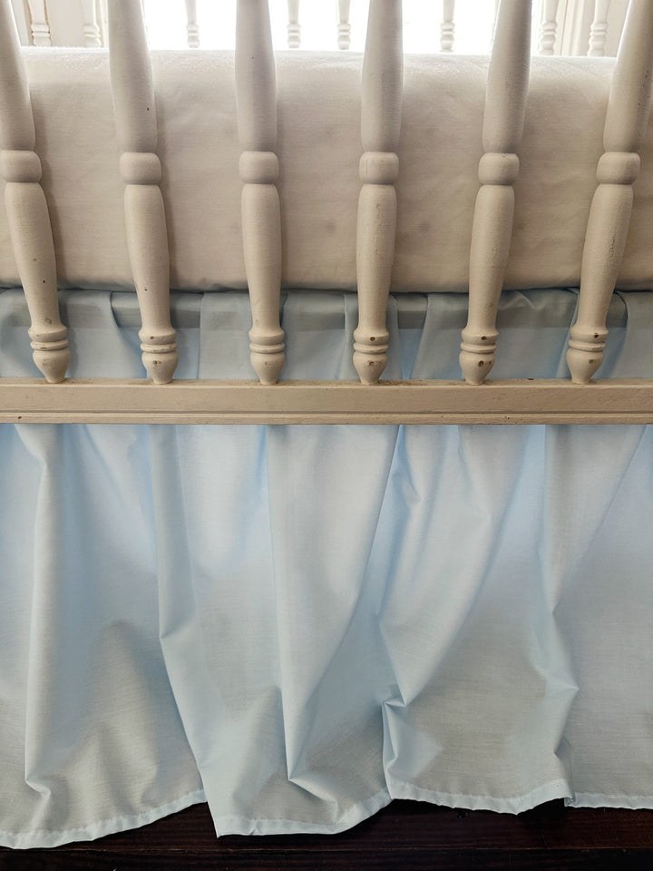Detail of the heirloom blue farmhouse crib skirt gathering between the turned crib spindles