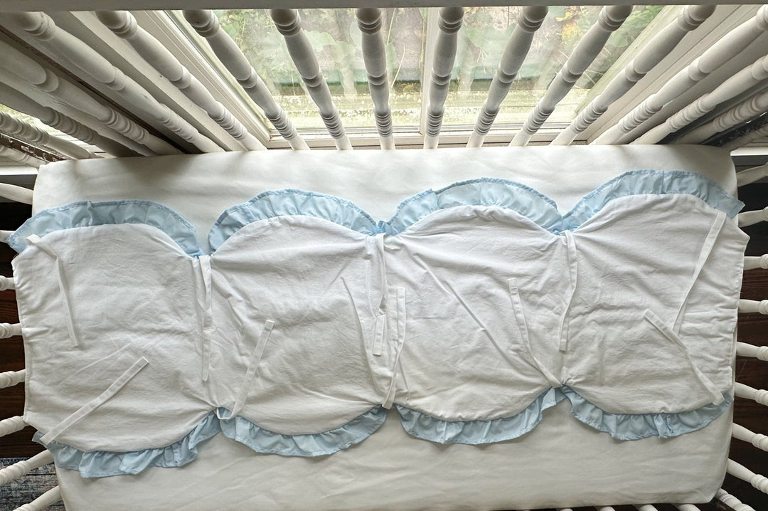 Overhead view of the white scalloped rail cover laid open, showing four heirloom blue ruffled scallops and white ties