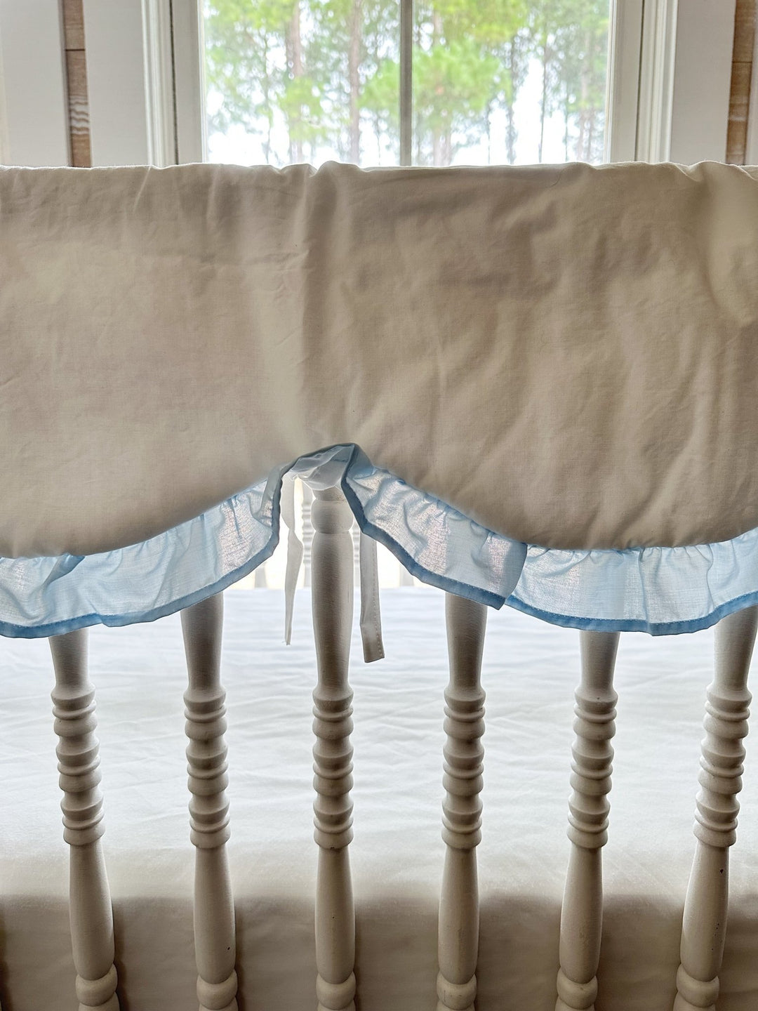 Close view of the scalloped rail cover edge where the heirloom blue ruffle meets the white cotton