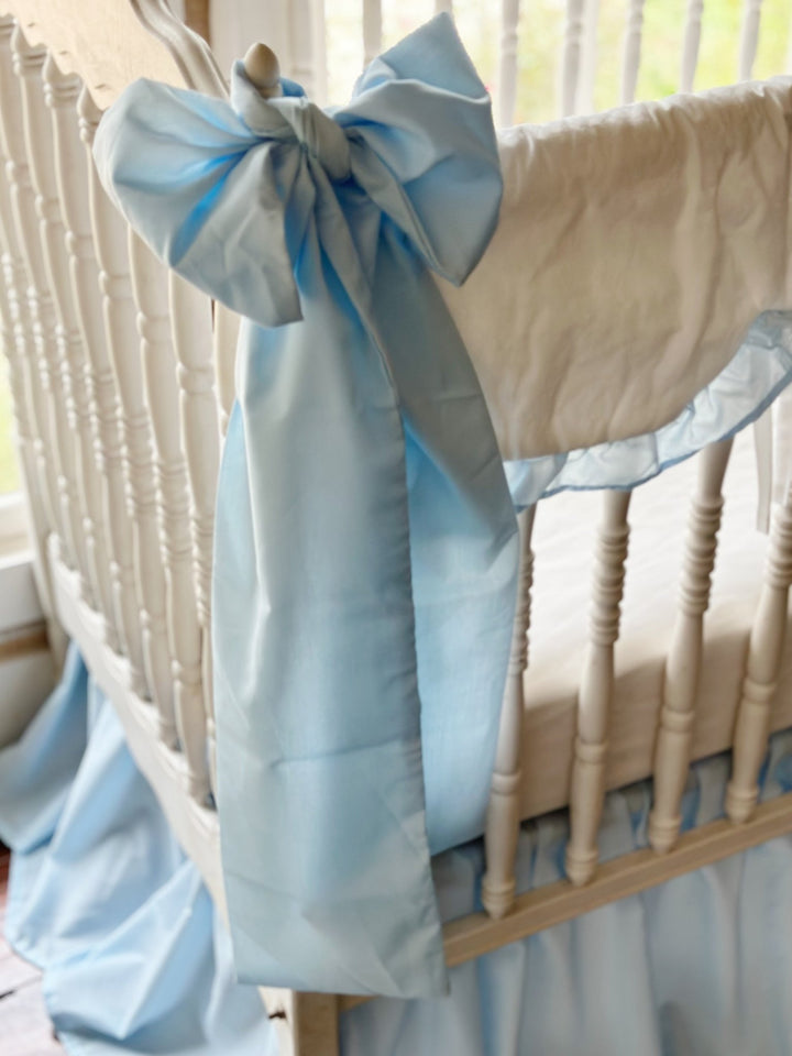 Large heirloom blue crib bow tied around the corner post with long tails falling toward the floor