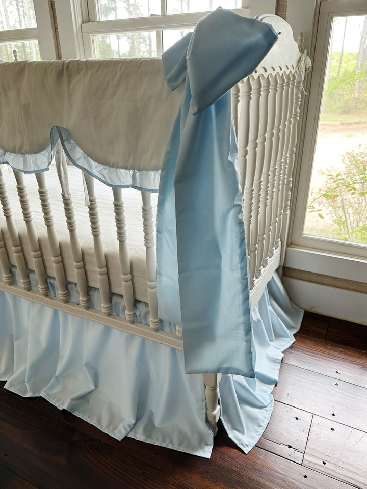 Heirloom blue bow draped over the crib end with the scalloped rail cover and gathered skirt behind