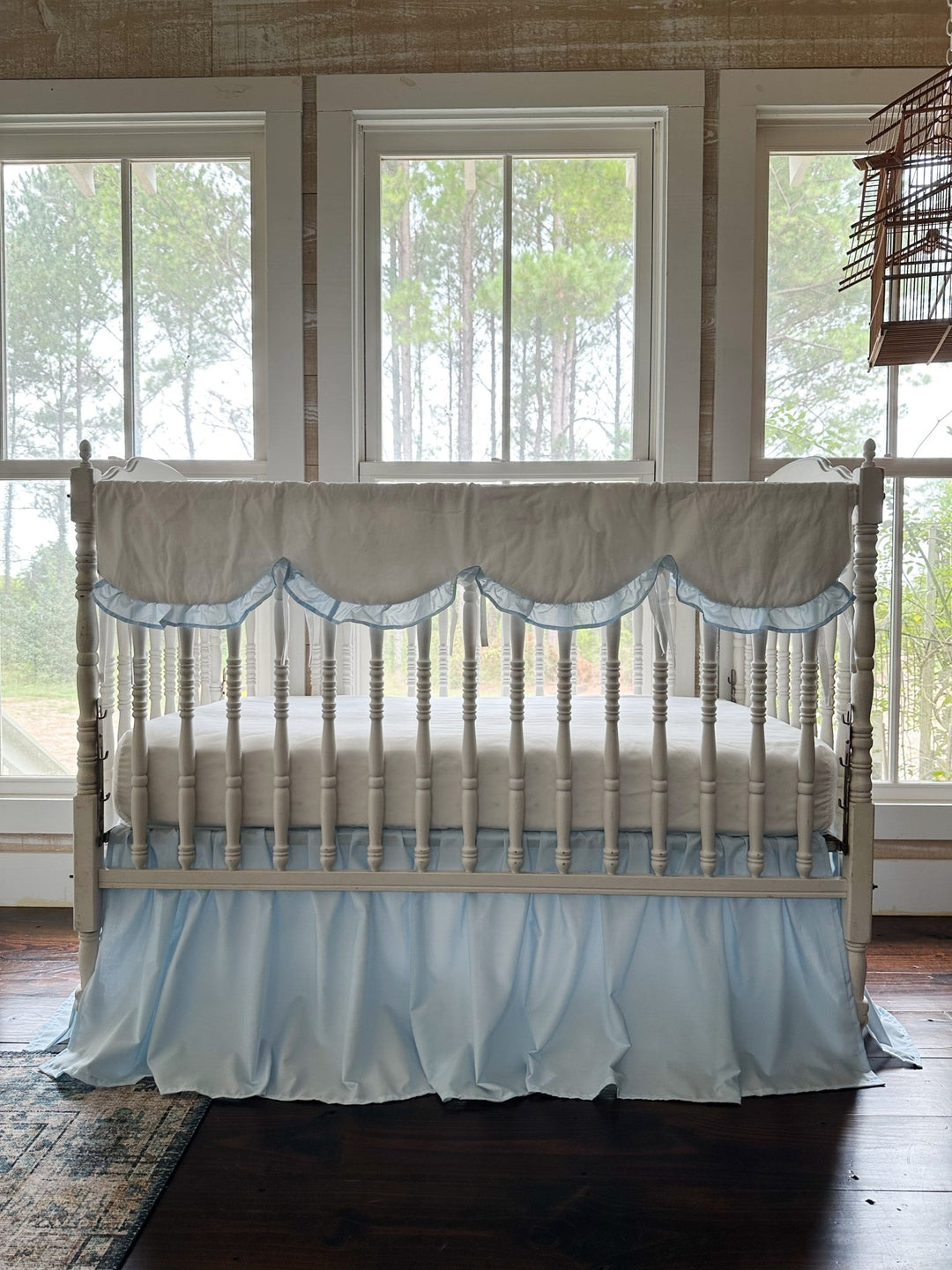 White scalloped crib rail cover with heirloom blue ruffle above a gathered blue farmhouse crib skirt