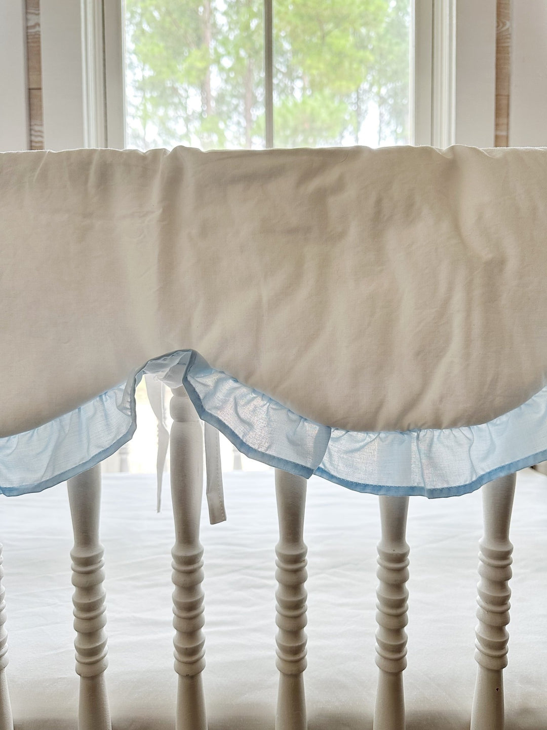Close view of one scallop where the heirloom blue ruffle meets white cotton, with a white tie hanging