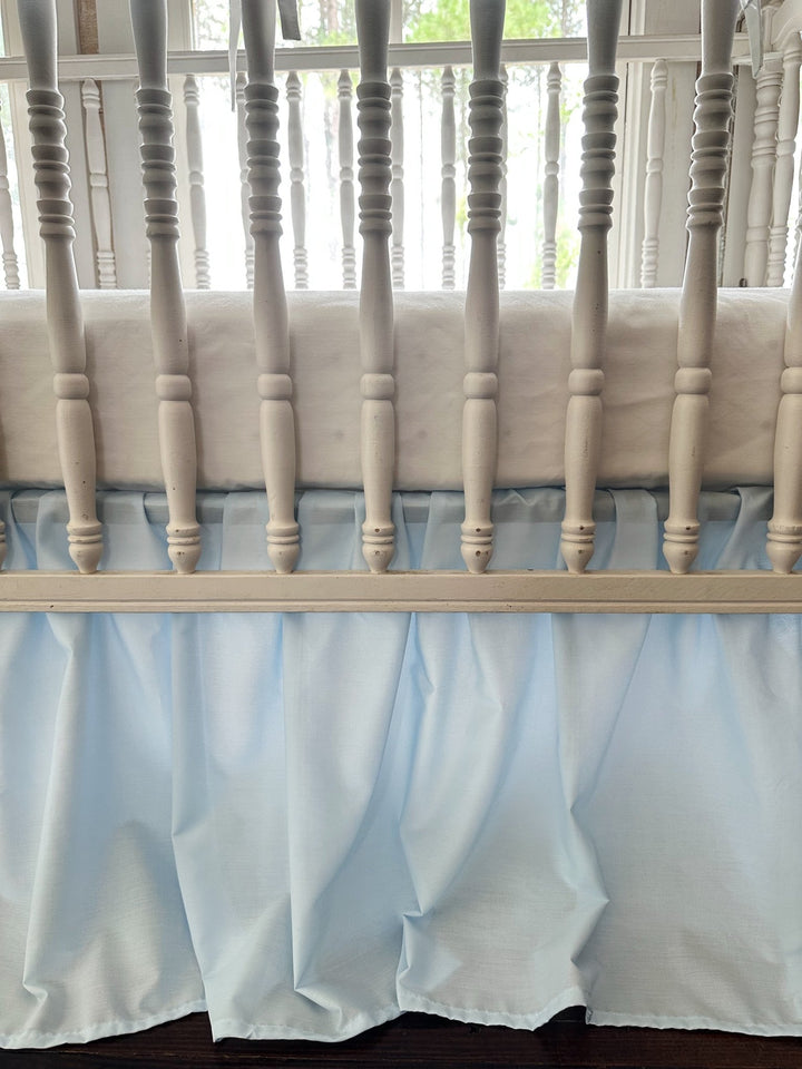 Heirloom blue farmhouse skirt gathering behind the turned spindles below the mattress line