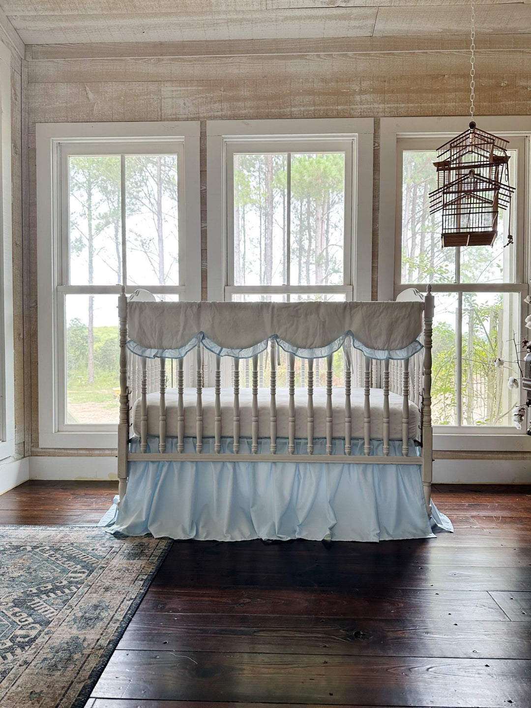 Corner of the crib where the scalloped rail cover ends and the blue skirt begins