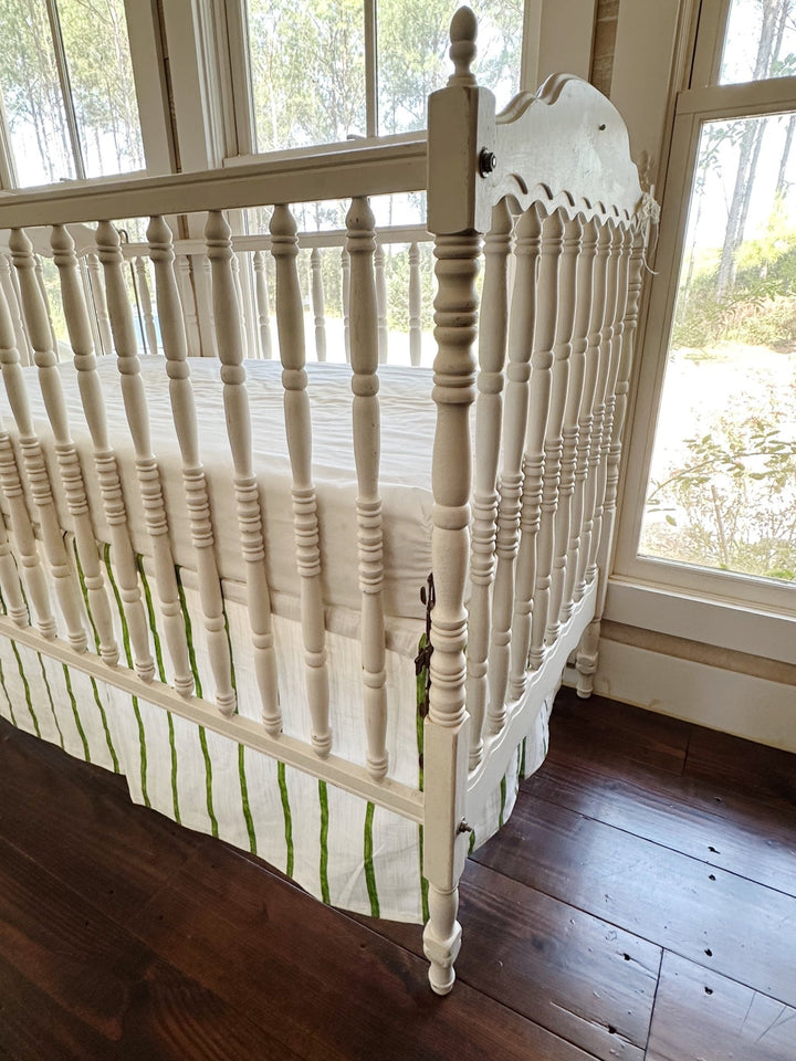 Corner view from the foot of the crib showing the skirt's split corner at the leg