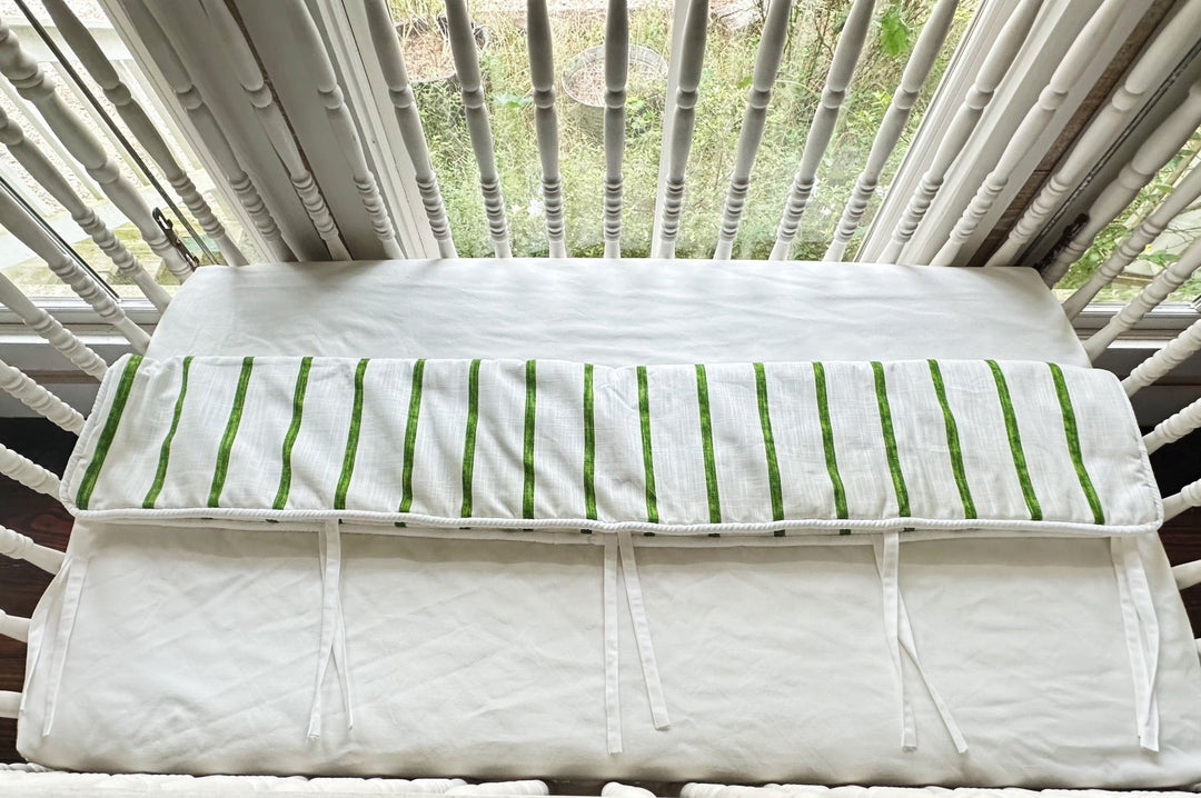 Overhead view of the rail cover folded over the crib rail, showing the plain white back panel