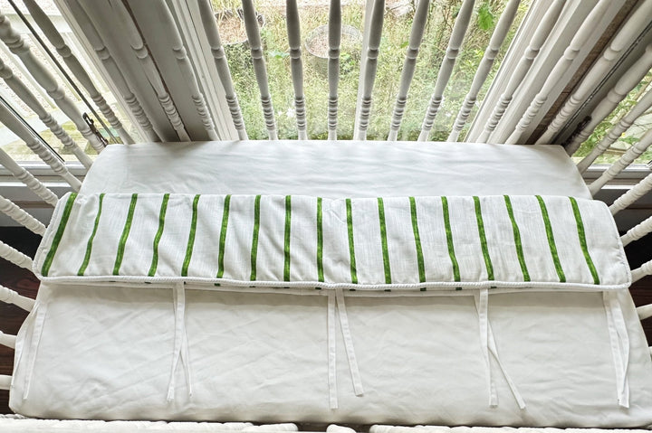Overhead view of the rail cover folded over the crib rail, showing the plain white back panel
