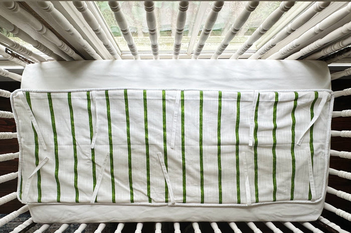 Cypress green and white striped tailored crib rail cover laid flat, every white tie spread out
