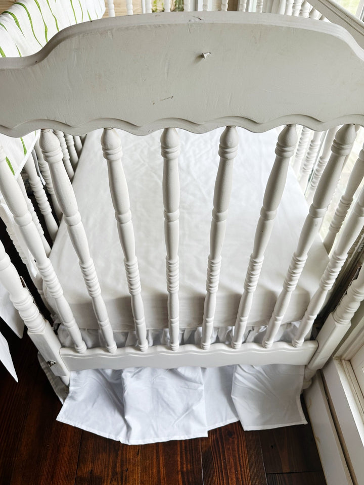 Foot of the crib with the scalloped headboard and the white farmhouse skirt at a 20-inch drop