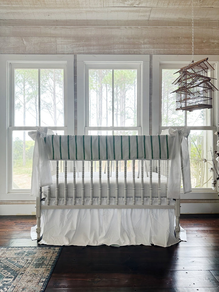 The striped crib set in a pine-paneled nursery with tall windows and a vintage birdcage