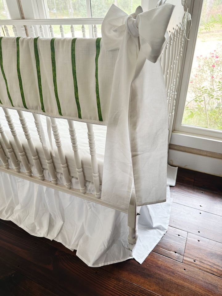 Side view showing the stripe running the length of the long crib rail above the white skirt