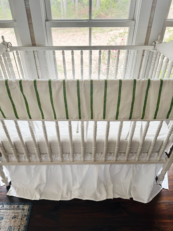 The full length of the rail cover from above, green stripes and white ties against the crib spindles