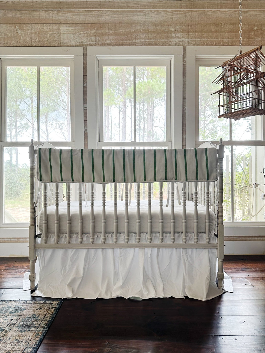 The two-piece striped set in a pine-paneled nursery with three windows and a hanging birdcage