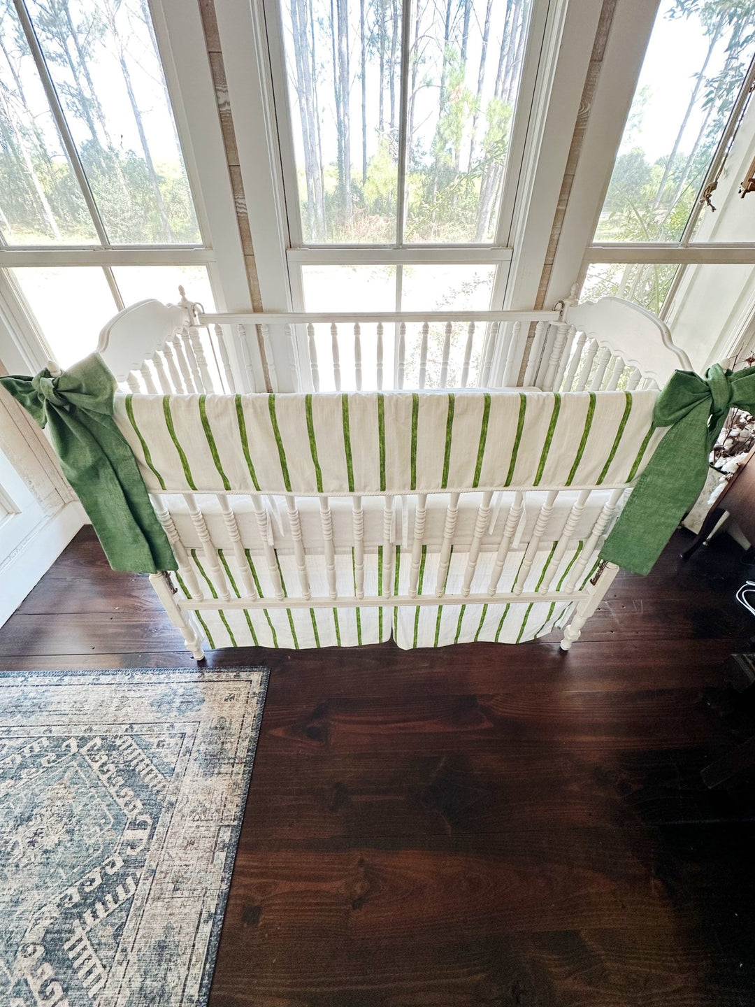Looking down into the crib at the striped rail cover, white sheet and striped tailored skirt