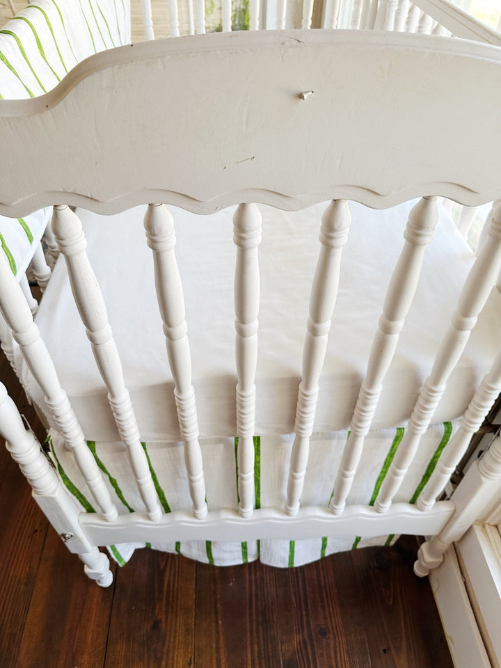 The scalloped headboard and turned spindles above the green striped tailored skirt