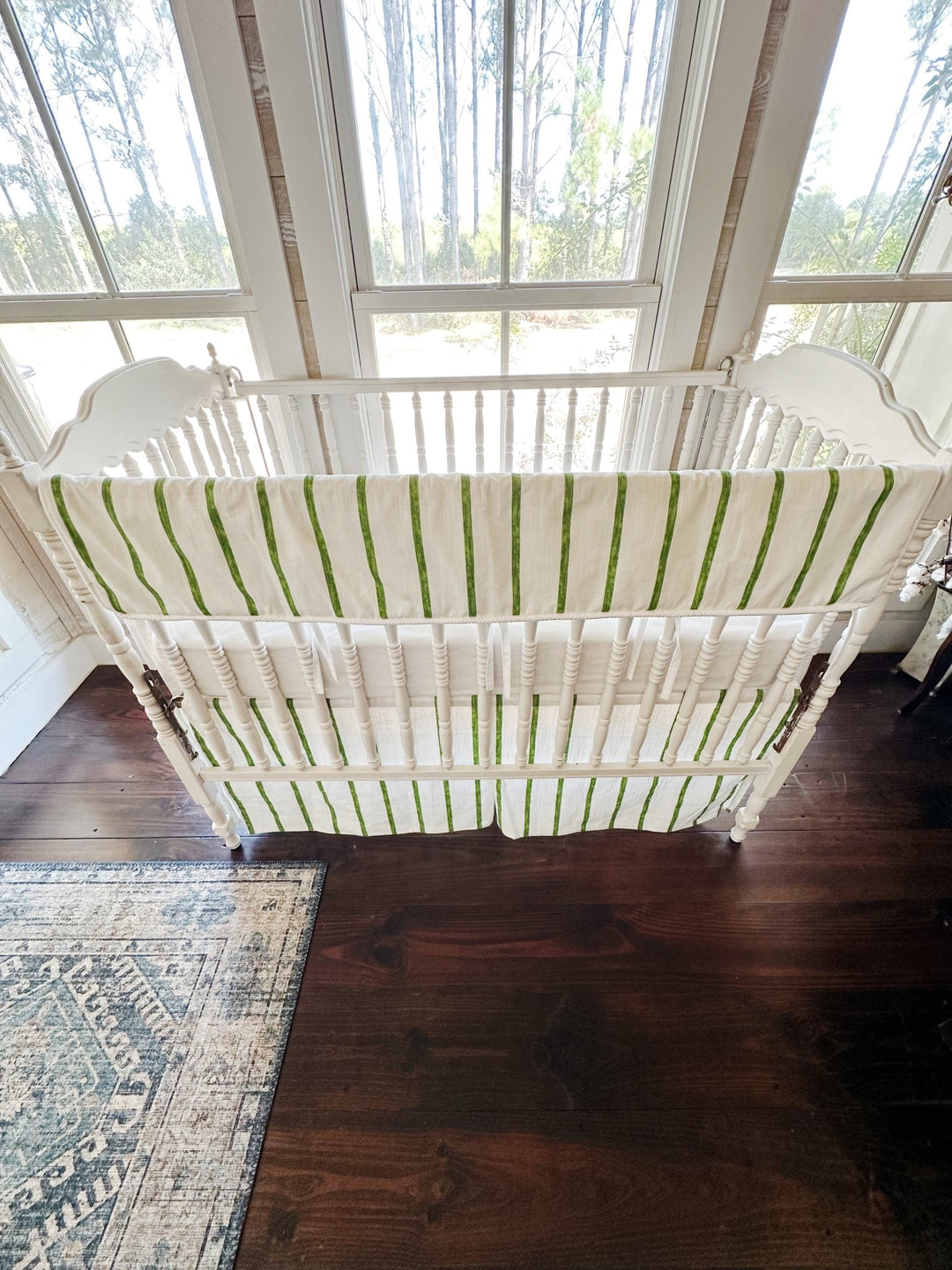 Overhead view of the whole crib showing the striped rail cover and the striped skirt below