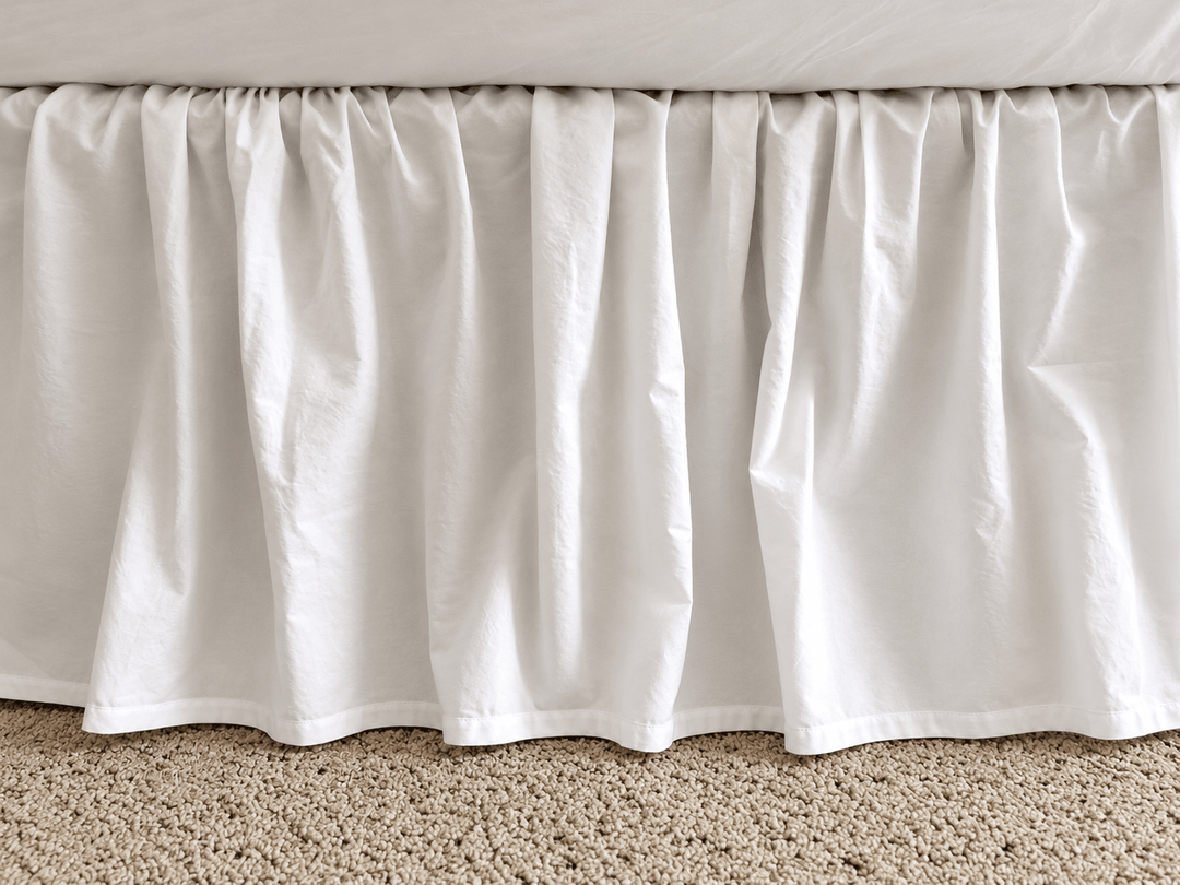 Full side view of the white farmhouse bed skirt showing even gathers along the length of the bed and a 20 inch drop to the floor