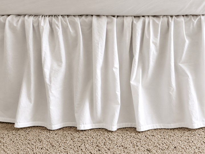 Full side view of the white farmhouse bed skirt showing even gathers along the length of the bed and a 20 inch drop to the floor