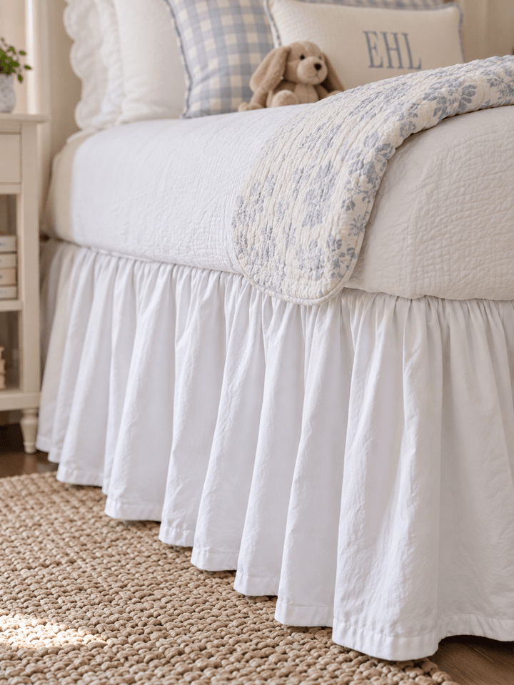 Close up of the gathered white farmhouse twin bed skirt falling to a jute rug - High Cotton Textile