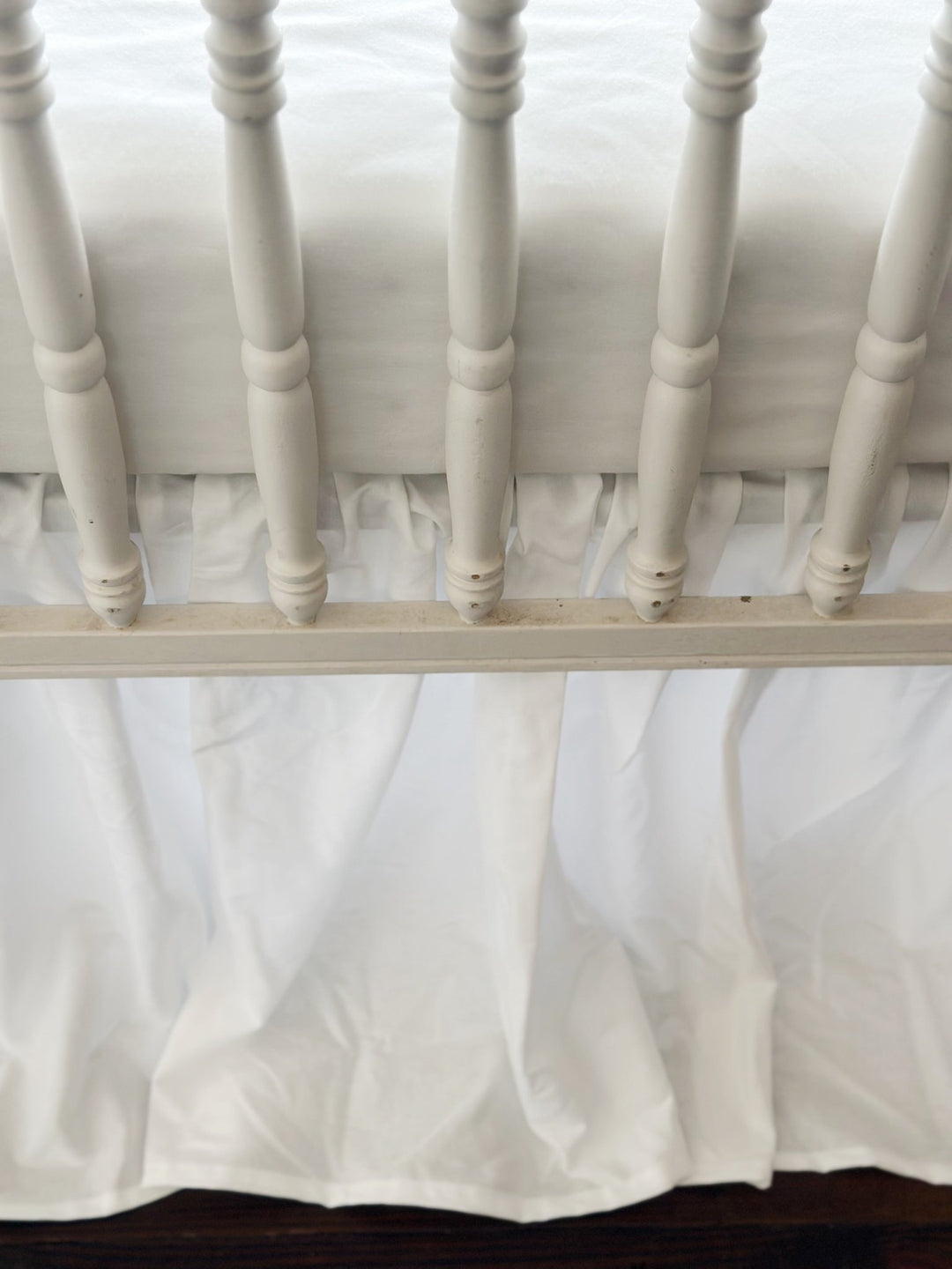 Detail of the soft even gathers along the top of the white farmhouse crib skirt