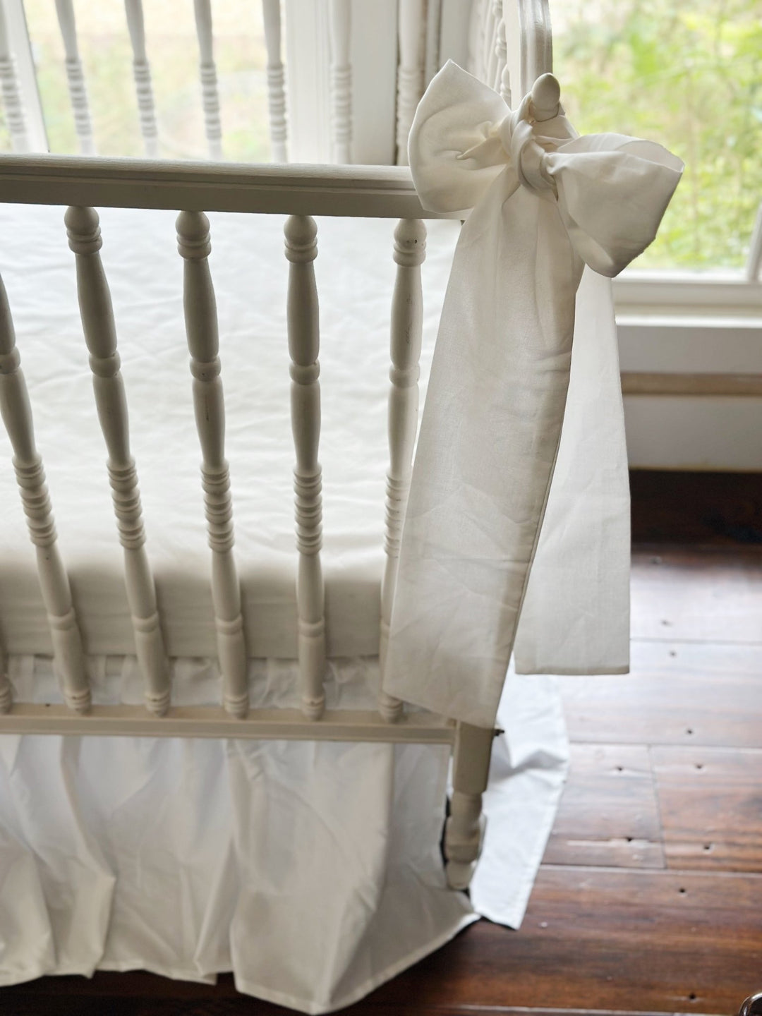 White bow seen from the side, its sash tails hanging past the gathered skirt