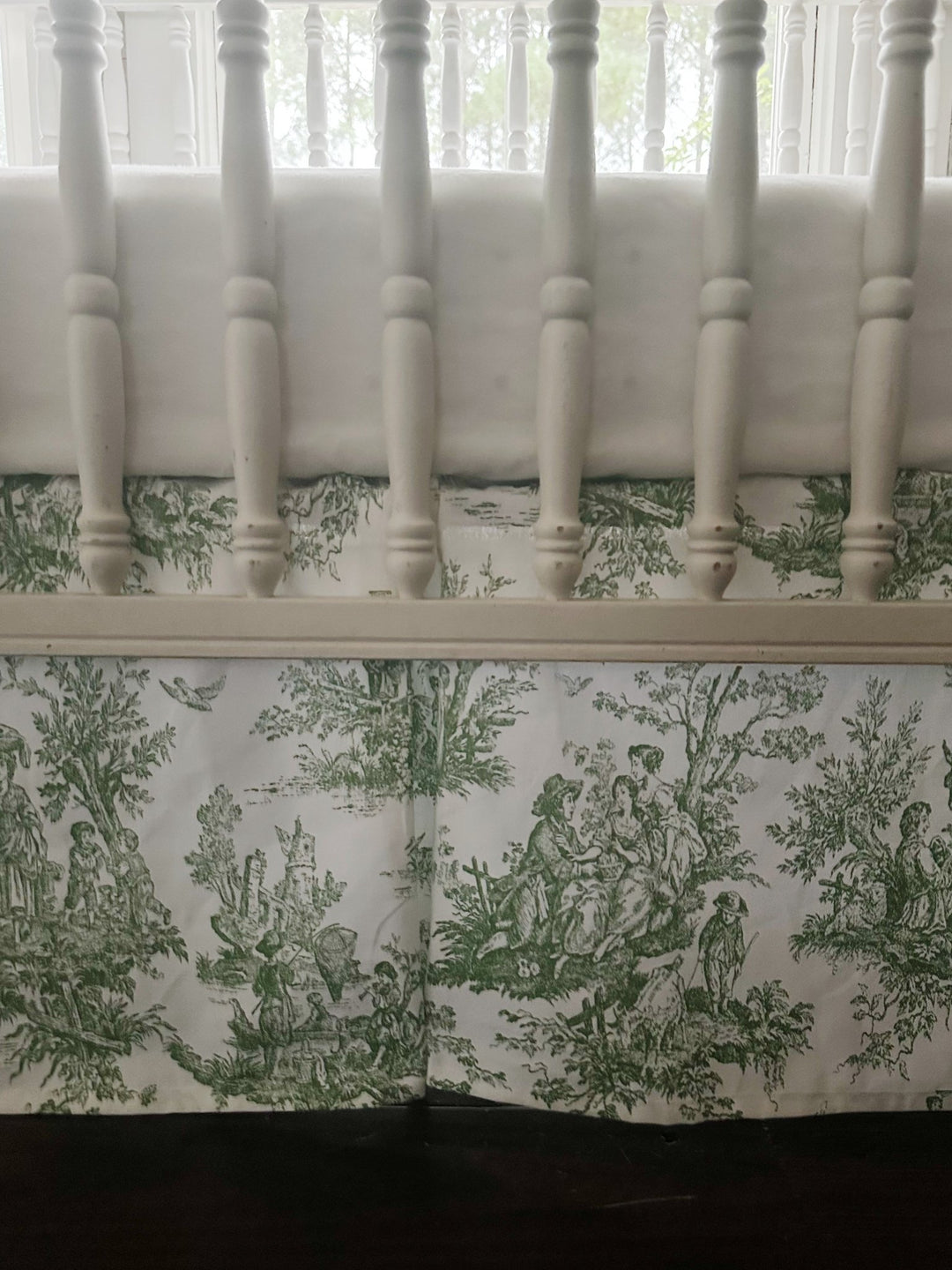 Detail of the white rail cover above the green toile skirt, showing the pastoral print and box pleat